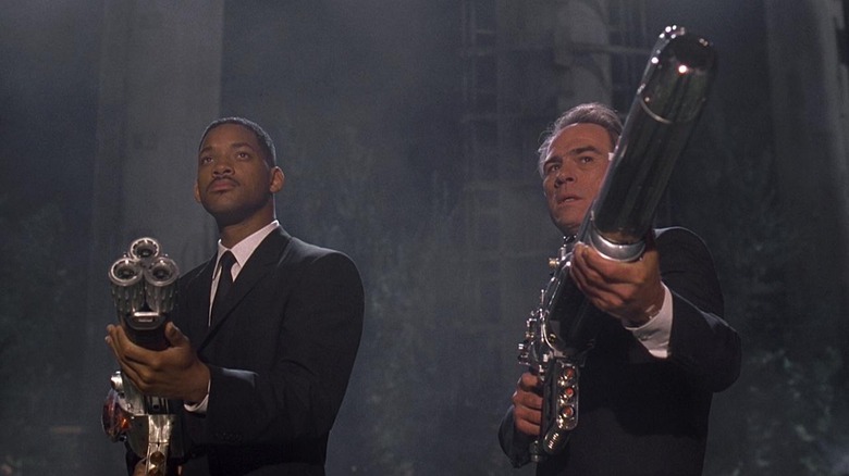 Agent J and Agent K aim space guns at a monster off screen.