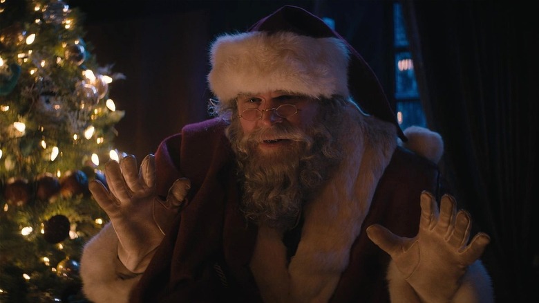 Santa Claus raising hands to signal peace to bad guy in "Violent Night" (2022)