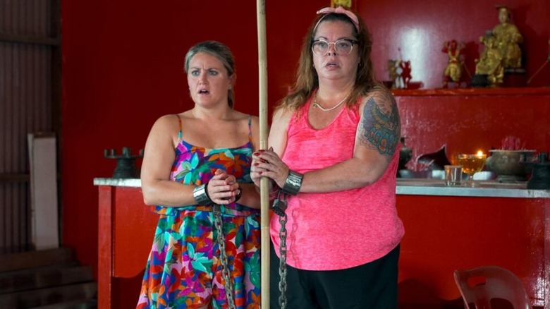 Two women chained to a pole in The Mole (2001)