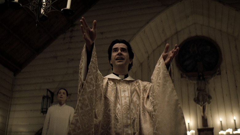 Father Paul/Monsignor Pruitt raises his hand in the church on "Midnight Mass" (2021)