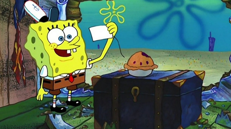 Spongebob standing before a pie with a bit taken out while reading a gift tag with a smile on his face