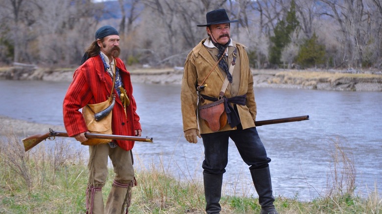 A pair of rugged fur trappers stand by a creek in "Into the Wild Frontier" (2022-2024)