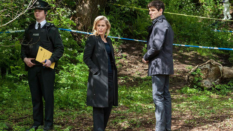 A uniformed officer, Detective Superintendent Stella Gibson, and Detective Sergeant Tom Anderson standing in the woods surrounded by police tape in "The Fall"