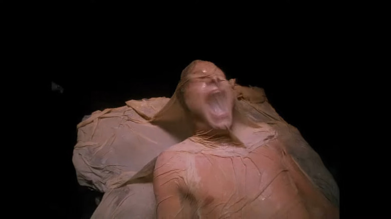 Man screaming and covered in beige material 