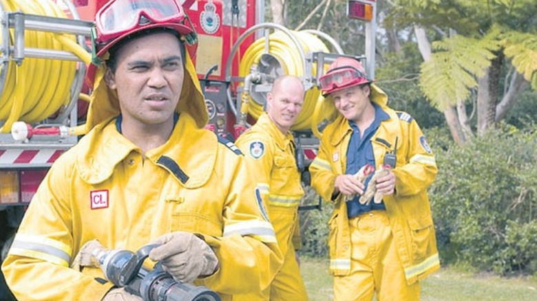 Patto pointing a hose as colleagues watch on in "Fireflies"