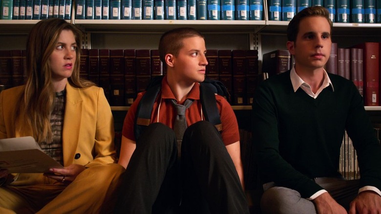 Three high school students on a library floor