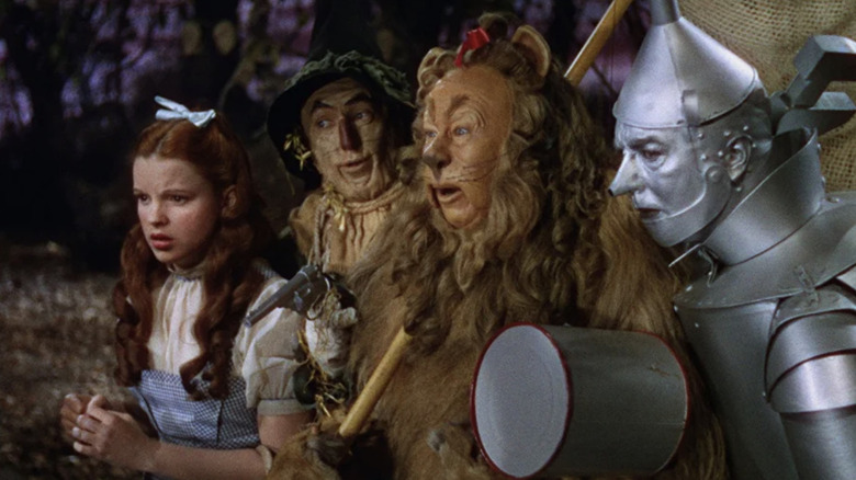 Dorothy, Scarecrow, Lion, and Tin Man march through the woods in "The Wizard of Oz" (1939)