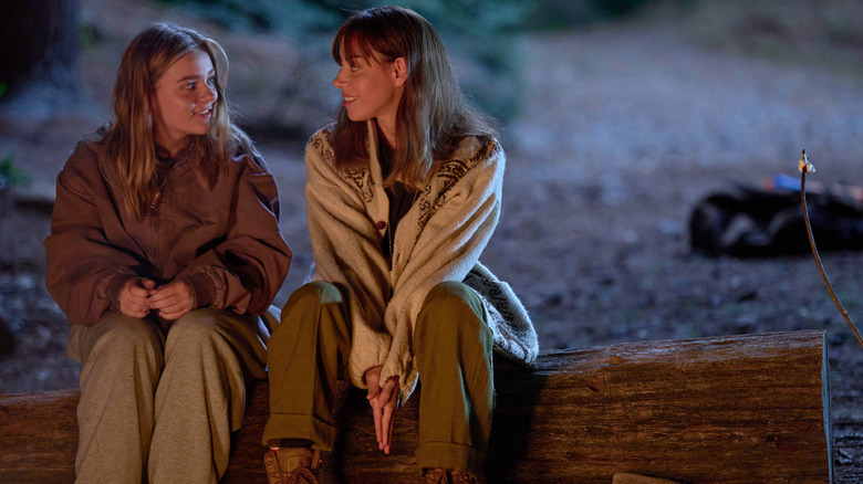 Teenager Elliot sitting at a campfire with her older self