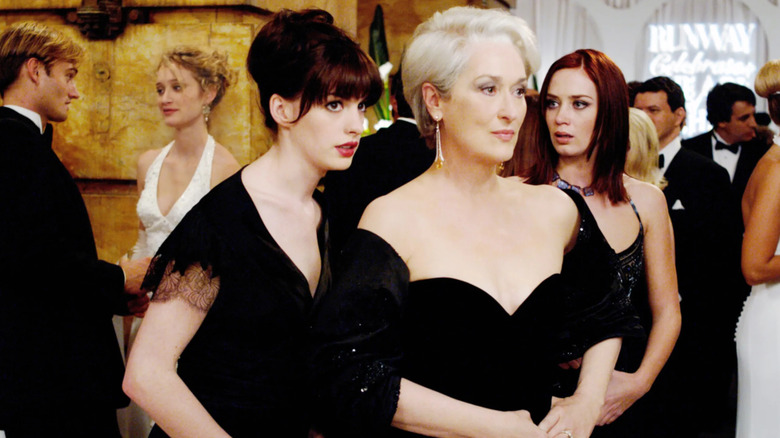 Andy and her coworker Emily flanking their boss, Miranda Priestly, at a formal event