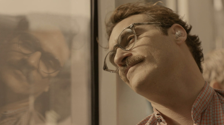 Smiling Joaquin Phoenix leans head against window