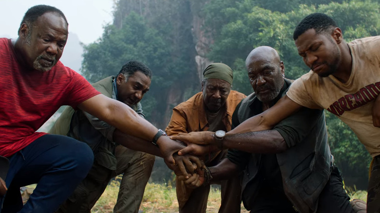 Five men hold hands in the jungle