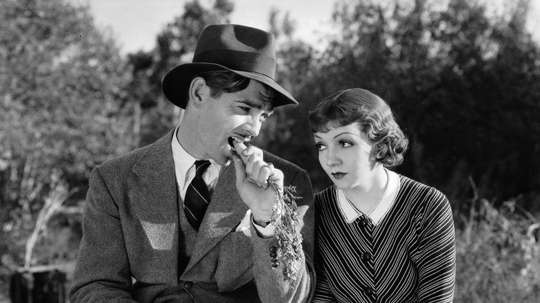 Gable eating a carrot sitting next to Colbert