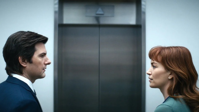 A man and woman speak at an elevator