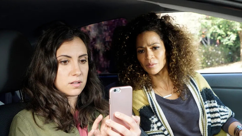 Two women look at a phone in car