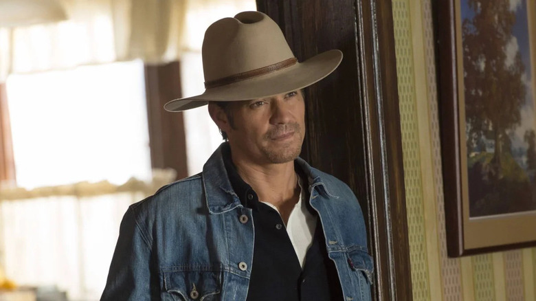 Raylan Givens stands in a doorway and smugly smiles