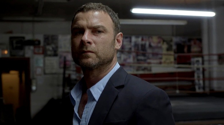 Ray Donovan stands in a gym in a suit