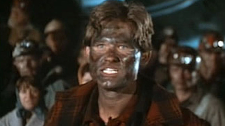 A grimy Kurt Russell reacts