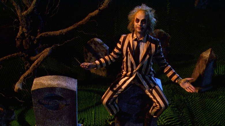 Beetlejuice sitting on gravestone