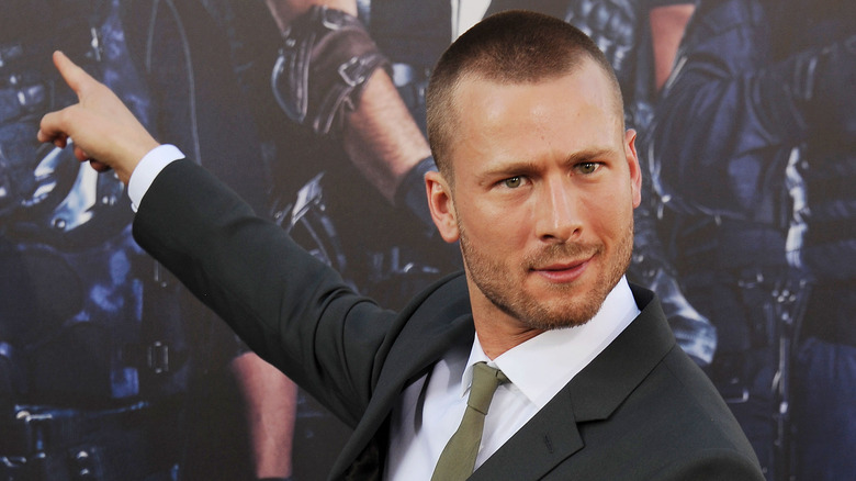 Glen Powell pointing at Expendables poster