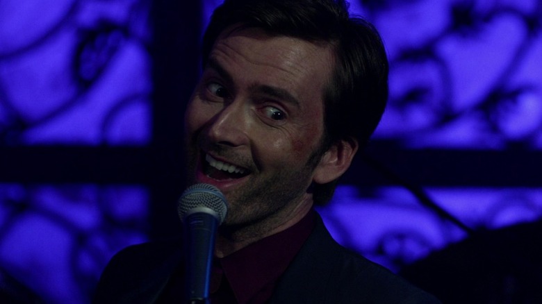 Kilgrave holding microphone and grinning