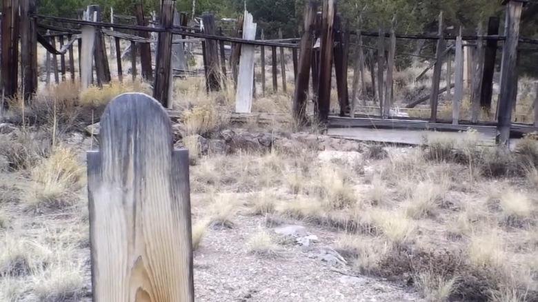 Wooden grave marker in front of a wooden fence