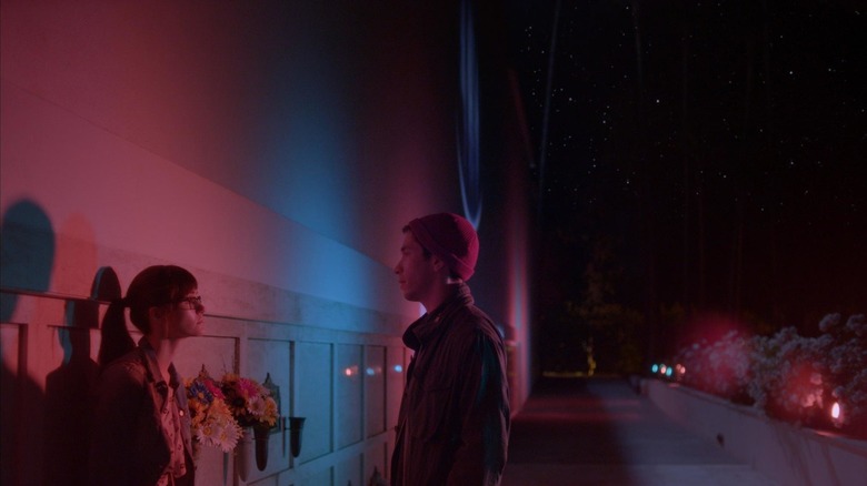 Dell and Kimberly talking against blue and pink lit wall in "Comet"