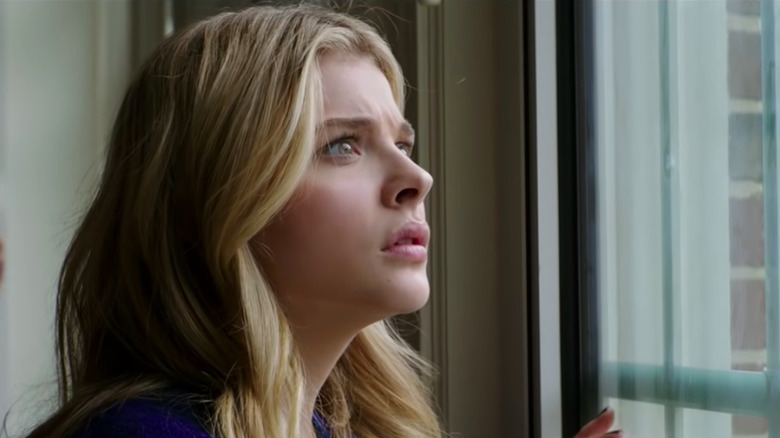 Cassie is surprised and worried as she looks out the window in The 5th Wave