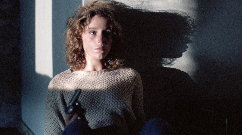 Abby sits against the wall with a gun in "Blood Simple" (1984)