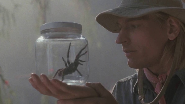 A man looking at a big spider in a jar