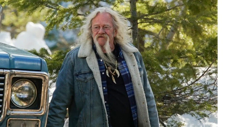 Billy Brown walks near a truck in the woods