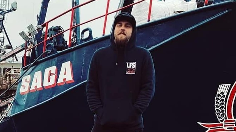 Ross Jones standing on a pier in front of a fishing boat