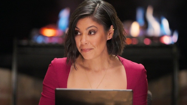 Alex Wagner smirking and raising an eyebrow at a computer on The Mole