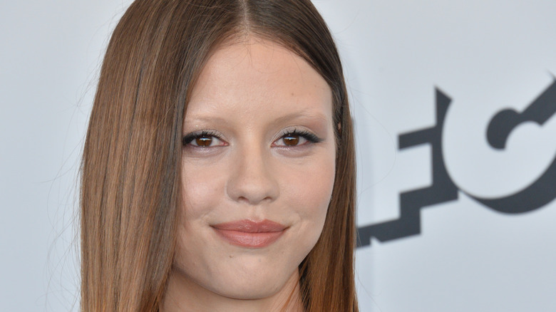 Mia Goth smirking on the red carpet