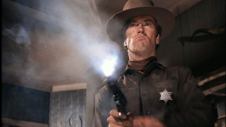 Marshal Jedediah Cooper firing a Single Action Army revolver while wearing a hat and badge in Hang 'Em High