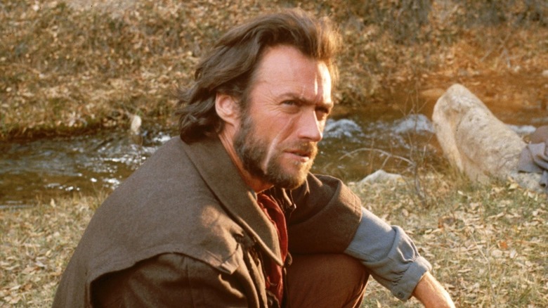 Clint Eastwood as Josey Wales sitting on the ground by a creek looking up