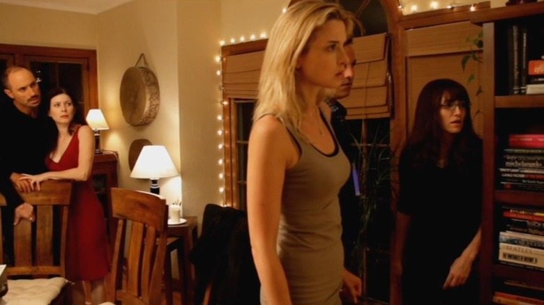 Friends stand in a living room in "Coherence" (2013)