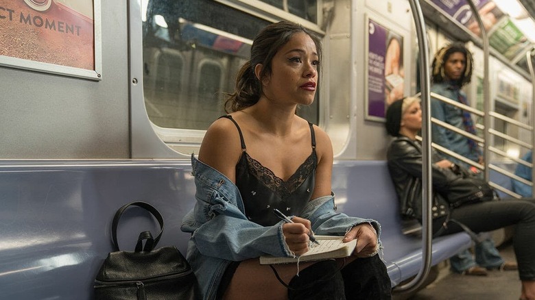 Jenny writing in a notebook on the subway crying in Someone Great