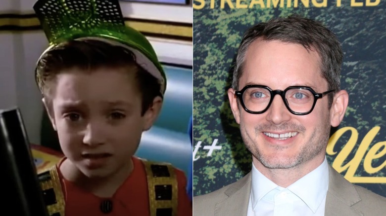 An unnamed child in "Back to the Future Part II" and Elijah Wood smiling while wearing glasses and a grey suit without a tie in 2025