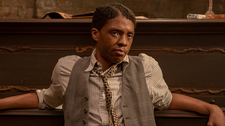 Chadwick Boseman leaning against piano