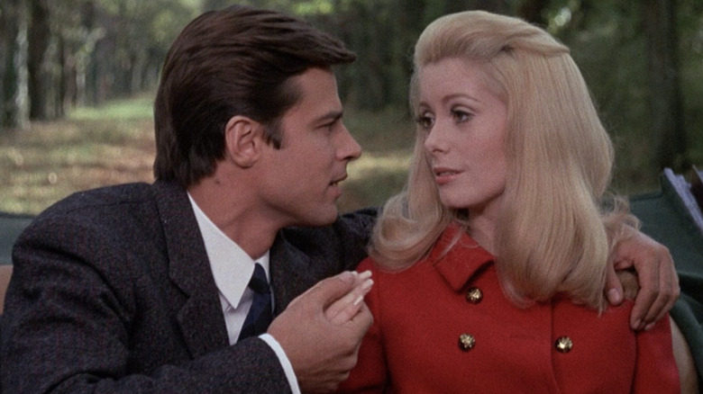 Man holds Catherine Deneuve's hand