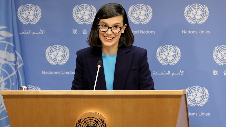 Millie Bobby Brown smiling behind podium