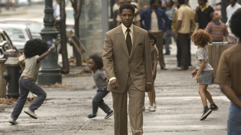 Frank Lucas walks down a busy city street while children play on the sidewalk behind him in "American Gangster" (2007)