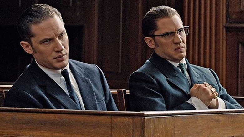 Reggie and Ron Kray shift uncomfortably while sitting in a courtroom witness box in "Legend" (2015)