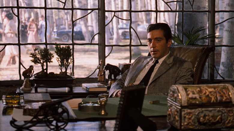 Michael Corleone leans back in his leather chair behind his desk, in front of a large window in "The Godfather" (1972)