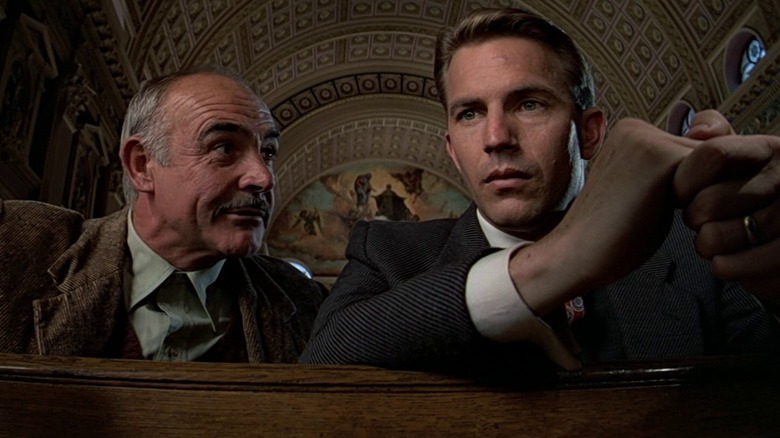 Jimmy leans over to talk to Elliott Ness while sitting in church in "The Untouchables" (1987)