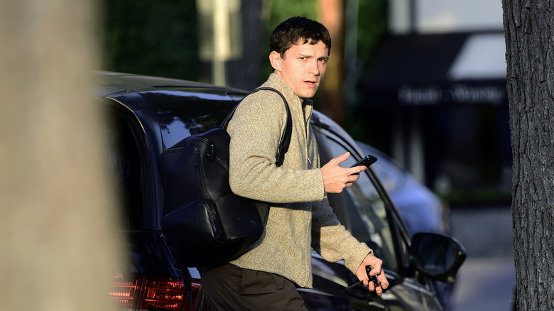 Tom Holland on his phone by car