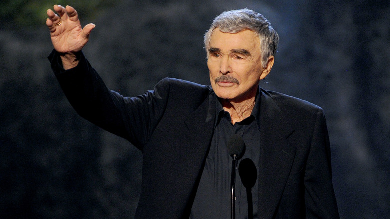 Burt Reynolds waves wearing suit