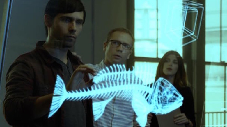 Three people observe a CGI fish