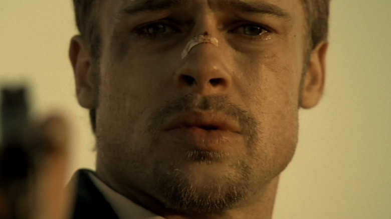 Upset Brad Pitt stares ahead holding gun