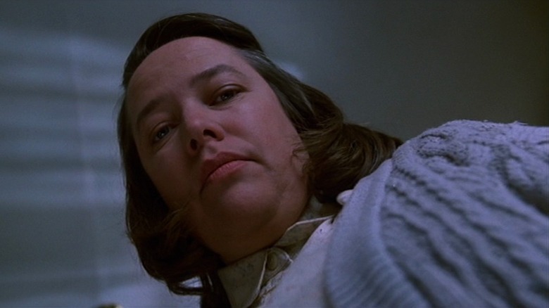 Annie Wilkes leans over Paul Sheldon